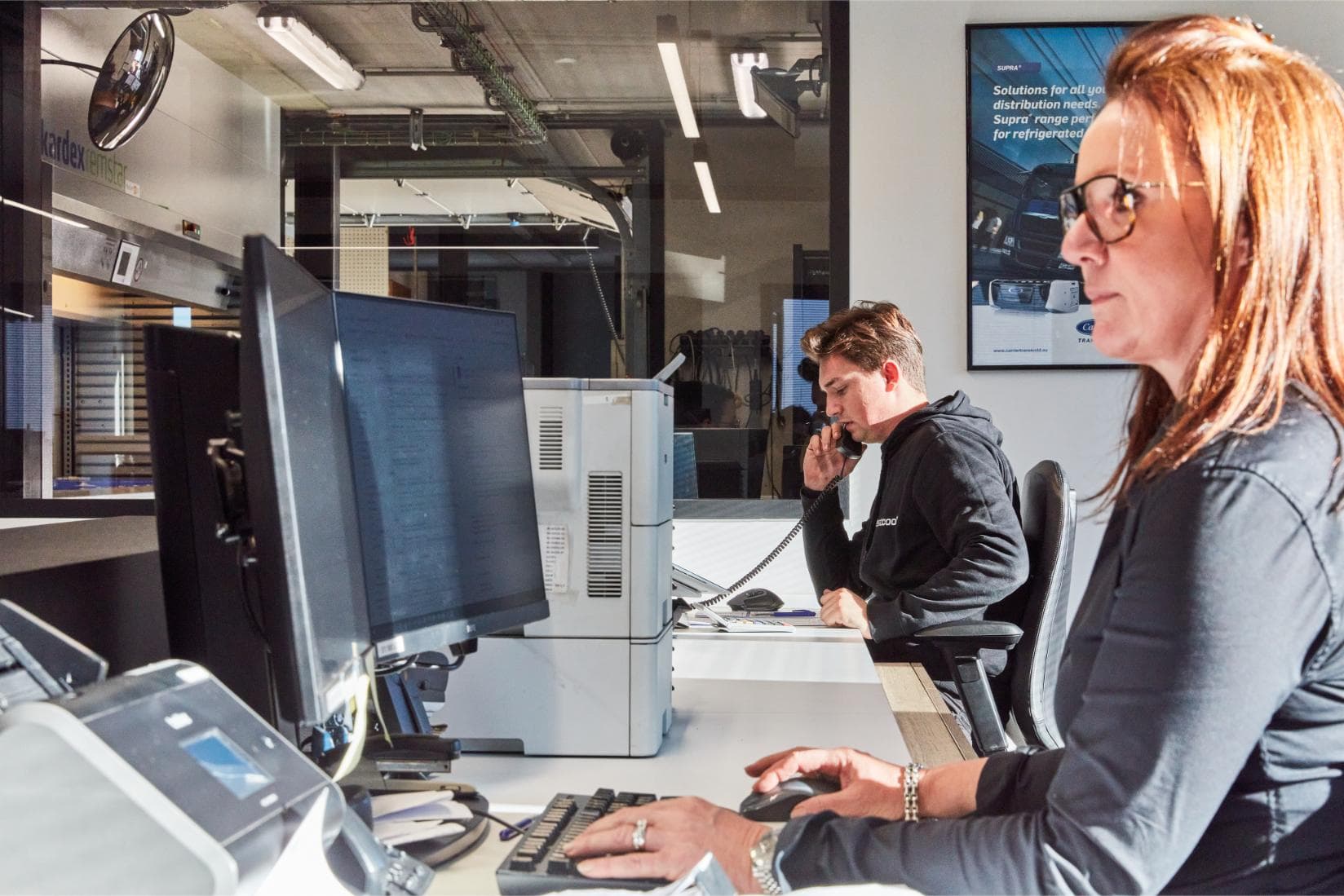 Two Westcool staff at the service desk in Hooglede, one at the keyboard and one on the phone
