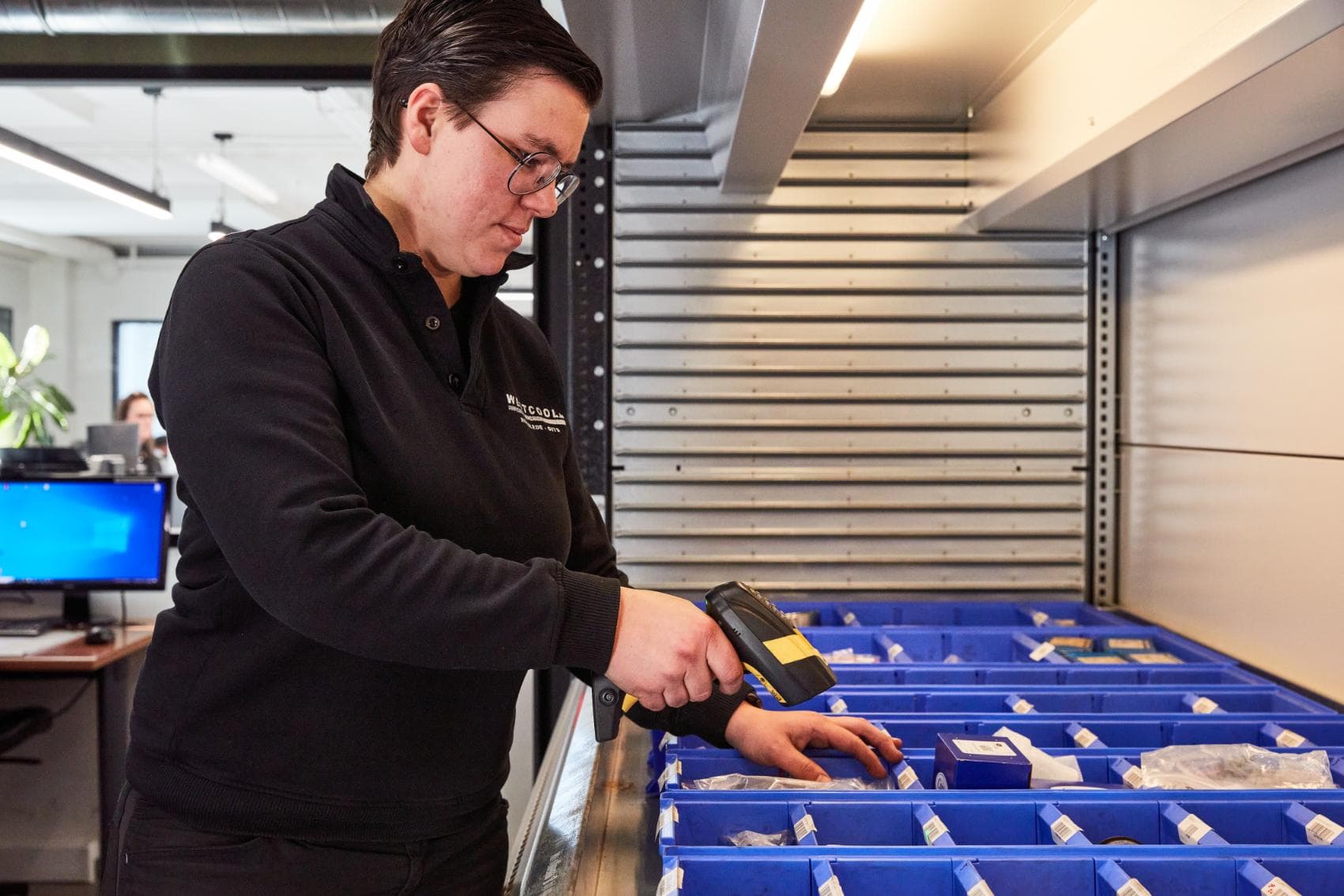 A Westcool warehouse worker scanning parts above the blue picking bins