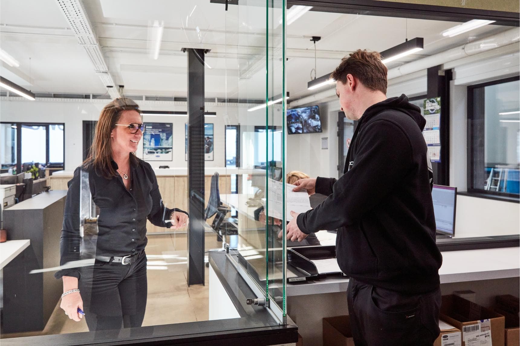 A Westcool employee handing a job sheet to a technician at the parts counter