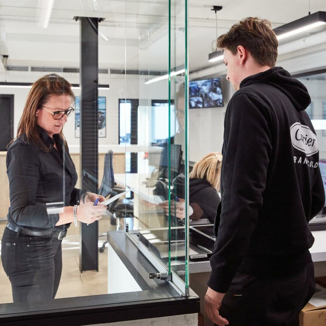 A Westcool employee with a job sheet at the parts counter, a technician facing her