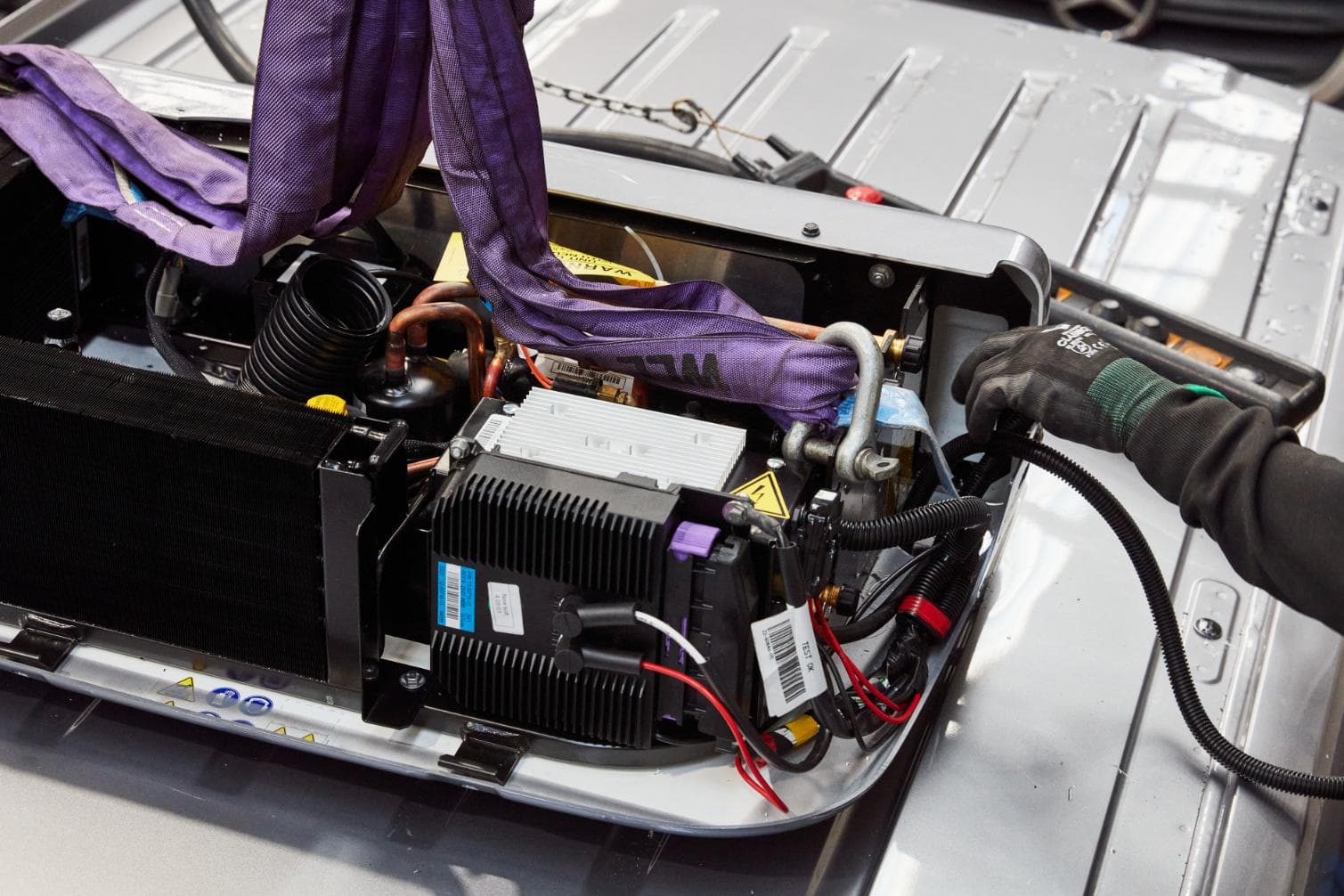 An opened refrigeration unit on the roof of a van, with the condenser and the wiring in view