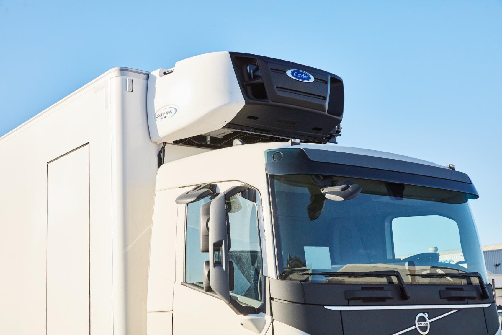 A Carrier Supra 1150 Mt refrigeration unit on the roof of a white Volvo truck