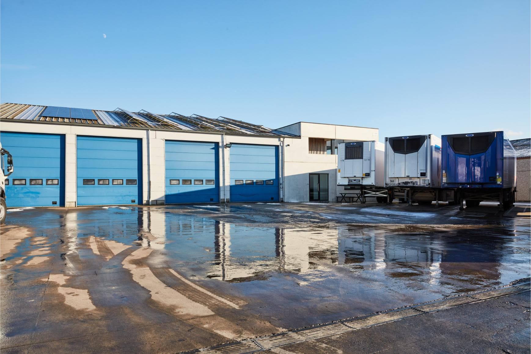 De vestiging van Westcool in Hooglede, met de blauwe poorten van de werkplaats en koelopleggers op de parking