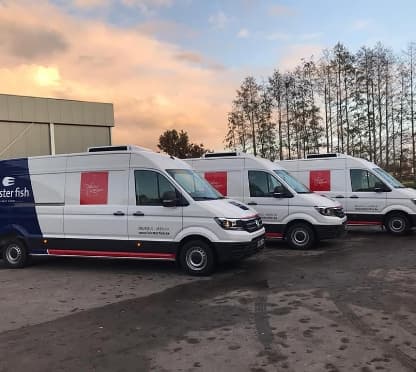 Drie omgebouwde witte bestelwagens met koelgroep op het dak, opgesteld op de parking